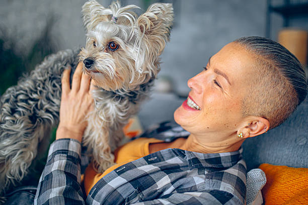 istock Woman Sitting on Sofa and petting her small dog 2220674467