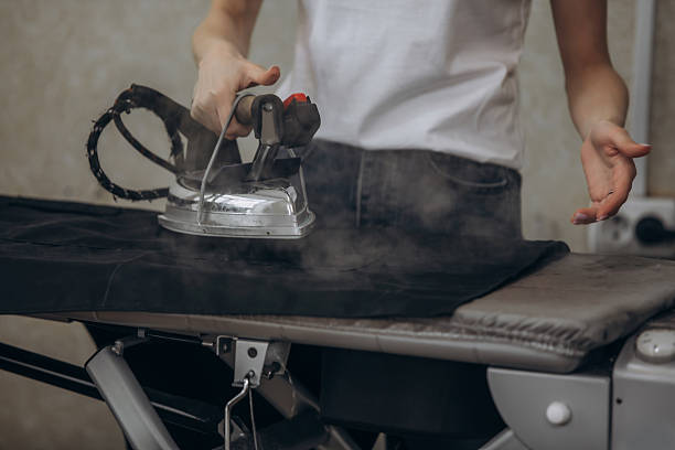istock Seamstress working with an iron in a sewing workshop hands close-up, small business 2220679381