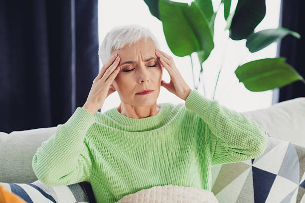 istock Mature woman sitting on a cozy sofa with a thoughtful expression in a modern apartment surrounded by houseplants 2220682593