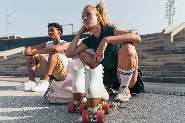 A woman is sitting on a bench putting on her roller skates.
