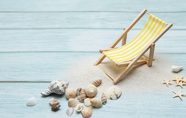istock Miniature deck chair on sandy beach with seashells inviting relaxation 2220684276