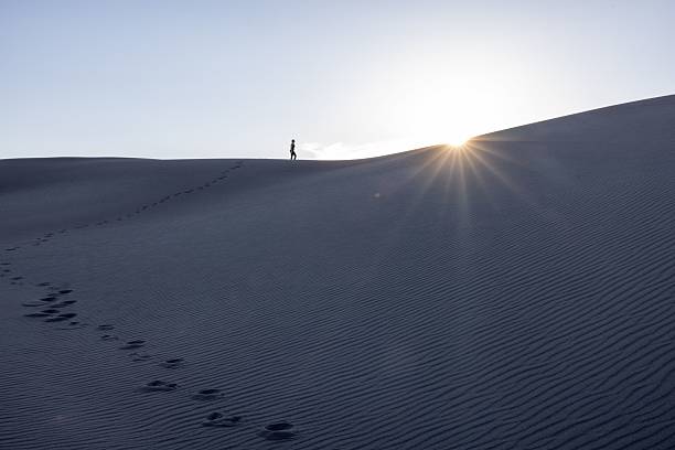 istock Lone figure on desert dune at sunrise. 2220684519