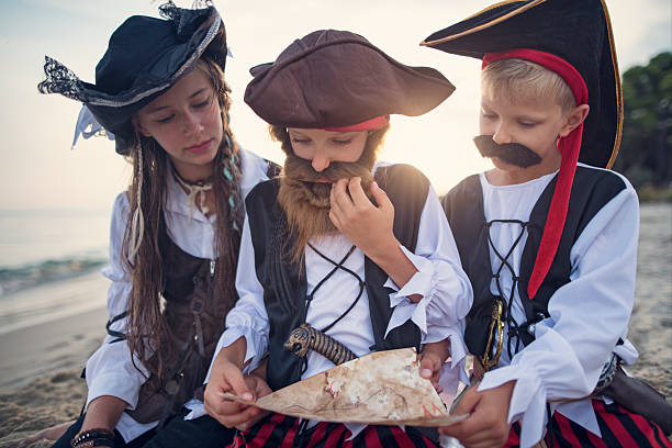 Kids enjoying pirate-themed beach adventure deciphering a treasure map.