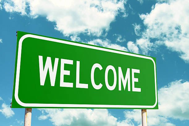 istock Welcome Green Road Sign with clouds sky background 2220685605