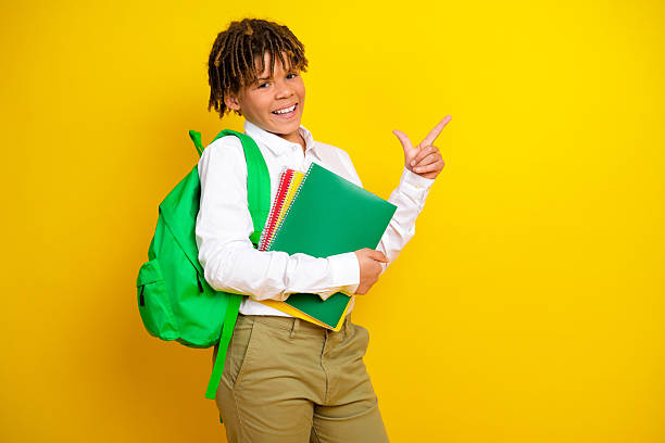 istock Happy schoolboy with backpack and notebooks gesturing on yellow background enjoying his day at school 2220689077