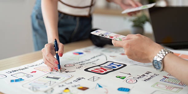 istock Hands-on Design Session. Young professionals collaborating on UX/UI concepts with sketches and digital tools. 2220691402