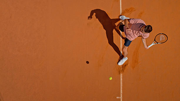 istock Dynamic Tennis Player Executing Powerful Forehand Shot On Clay Court With Dramatic Shadow Cast 2220693050