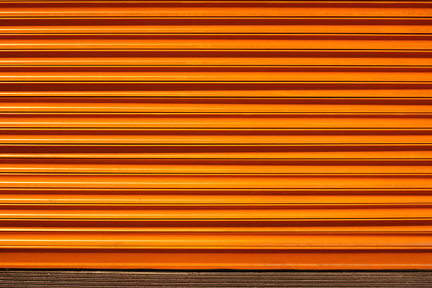 istock Orange colored shutters that protect warehouses and shops from environmental conditions and ensure their safety 2220693723