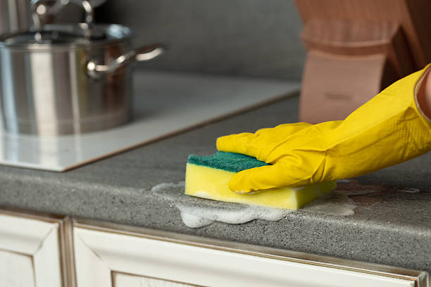 istock Woman's hands in yellow gloves cleaning counter top in kitchen 2220694129