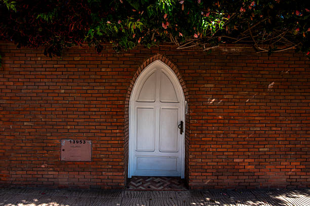 white wooden door with pointed arch on ashlar wall and green hedge