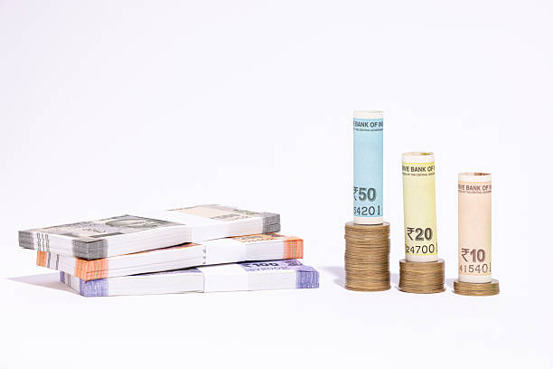 Horizontal click of scattered Indian currency coins spread or scattered randomly over two open spread hands like alms in beggar's hands. The coins are metallic shiny silver colored and of varied denominations.