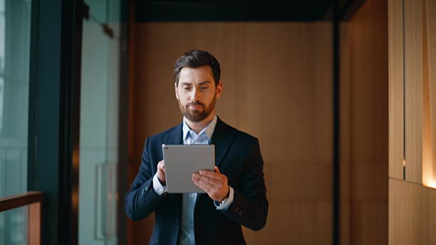 istock Entrepreneur browsing tablet walking hallway office closeup. Smiling businessman 2220695997