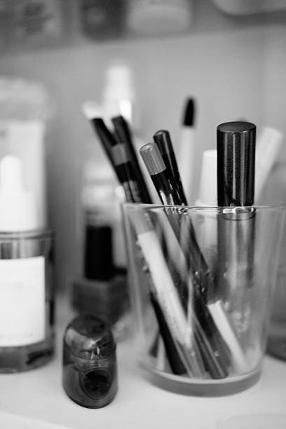 A monochrome image of brushes used for skin care and hygiene, displayed in a container on a bathroom shelf.