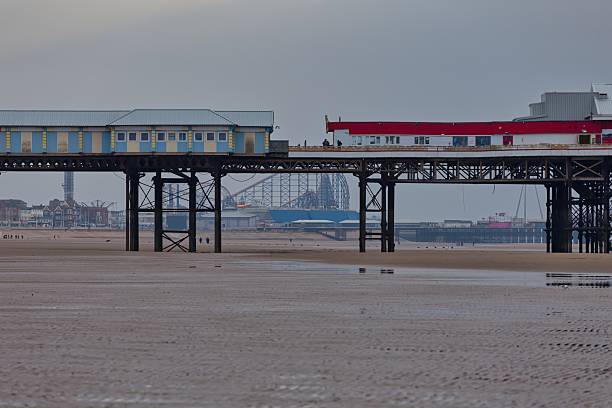 A pier stretches out over a sandy beach under an overcast sky in Blackpool - Lancashire - Great Britain