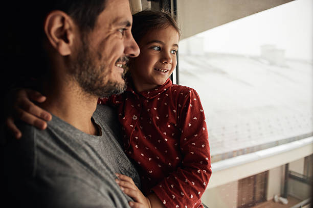 Beautiful girl and father bonding early in the morning by the window on an winter day.
