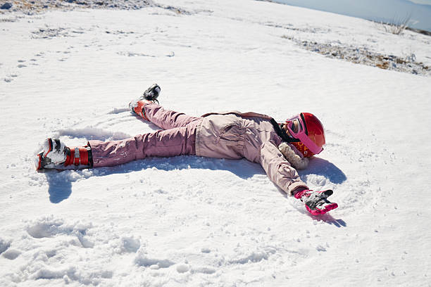 Winter portrait of a beautiful girl laughing and having a lot of fun in snow. She is making snow angel.