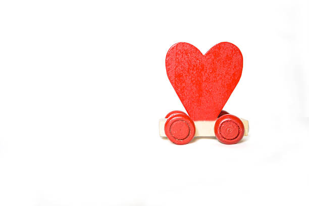 Red heart on wooden cube with yellow truck isolate on white background, love and romance concept, valentine card background idea