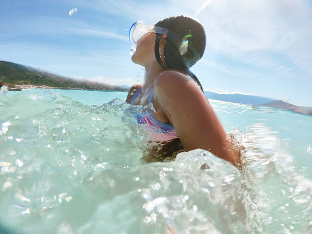 Young caucasian girl jumping into waves. She is swimming and diving in clear turquoise colored sea.