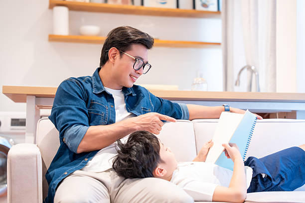 istock Father and child bonding at home reading a book together on a comfortable sofa 2220699794
