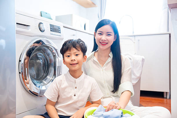 istock Mom and son are doing laundry spending time together in a brightly lit laundry room Smiling 2220700195