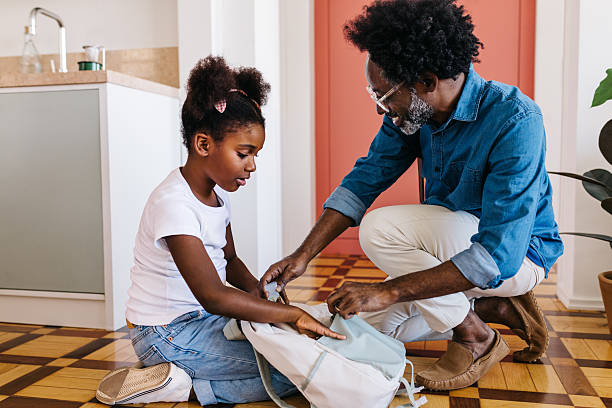 istock Happy father and daughter packing school bag together 2220700709