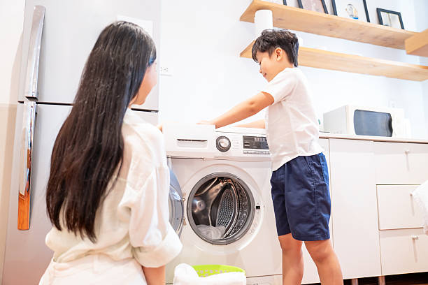 istock Child helping with laundry at home with parent in bright modern kitchen environment 2220701465