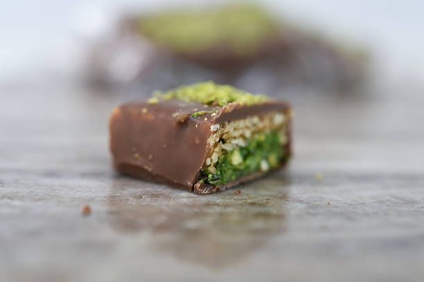 Chocolate Pistachio Bar with Wafer Layers cut in half to showcase its intricate layers with chocolate coating, thin crispy wafer layers, and green pistachio filling closeup side view of sweet treat