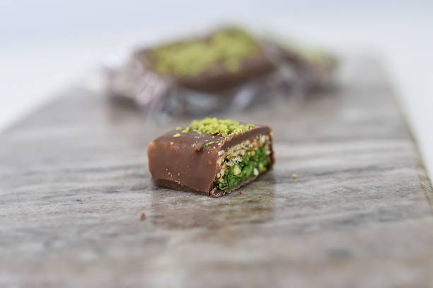 Chocolate Pistachio Bar with Wafer Layers cut in half to showcase its intricate layers with chocolate coating, thin crispy wafer layers, and green pistachio filling side view of sweet treat