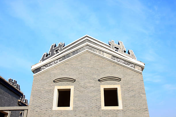 A close-up view of traditional Chinese roof tiles with a decorative ridge ornament, set against a clear blue sky. The image captures the intricate craftsmanship and cultural significance of the architecture. Visual style is realistic with vibrant colors, conveying a sense of historical elegance. Potential usage includes architectural studies, cultural documentation, or design inspiration.