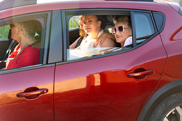 istock Bride and friends leaving wedding in red car 2220703132