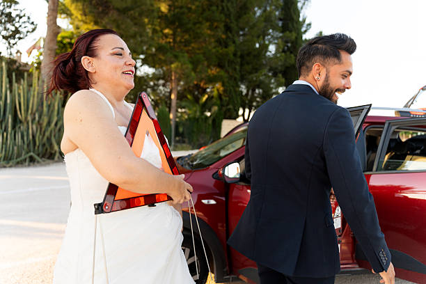 Newlyweds handling a car breakdown on their wedding day, placing a warning triangle for safety