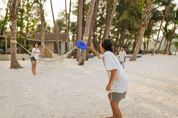 Father is playing frisbee with his kids on a tropical beach during a vacation