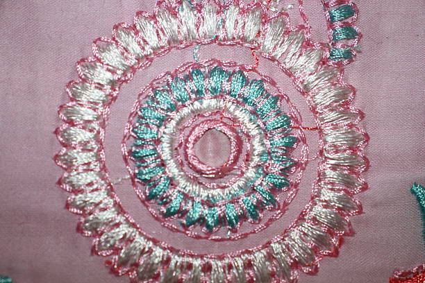 istock Intricate spiral embroidery on pink fabric. 2220706690