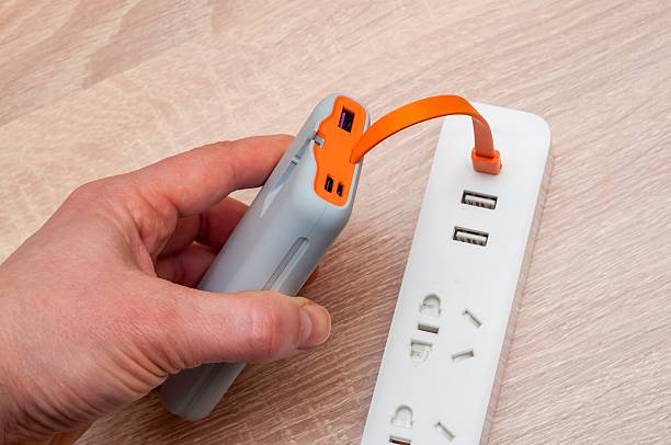 istock A hand plugging a power bank into a power strip for charging on a wooden surface. 2220707462