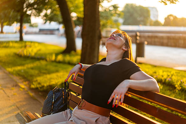 istock Young Woman Relaxing On A Park Bench 2220709786