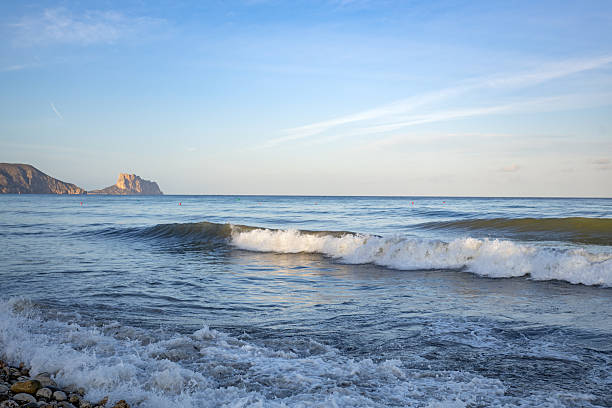 Altea. Alicante. Spain. Gentle waves lap the shore as the sun sets, casting a warm glow on the iconic calpe rock in spain, creating a peaceful and serene atmosphere