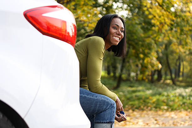 istock Female driver sitting on a car trunk 2220713129