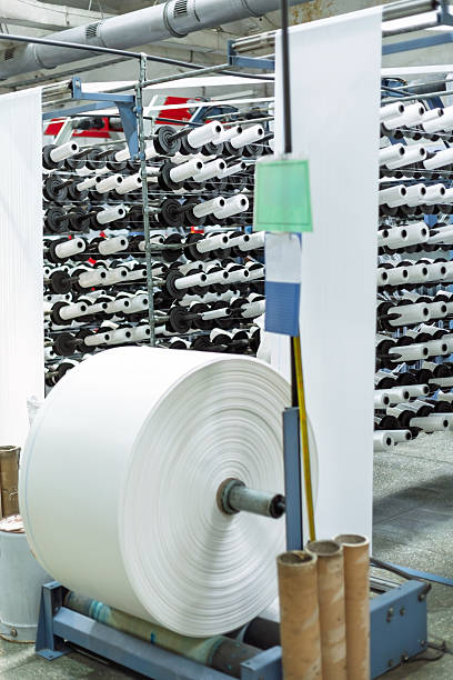 istock Large roll of white polypropylene fabric winding onto a spool in a factory 2220718661