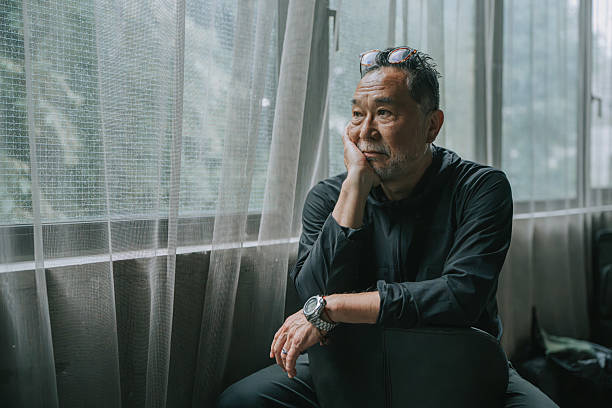 istock Mature Japanese Man Sitting by Window in Reflective Mood 2220718809
