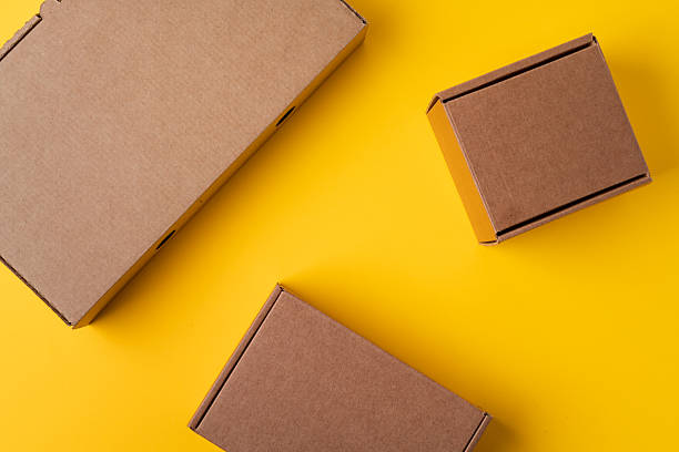 istock Beige cardboard boxes on yellow background, close up 2220719626