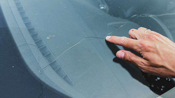 istock Man s hand pointing at a long crack on a car windshield, highlighting damage on the glass surface under daylight, automotive concept 2220725968
