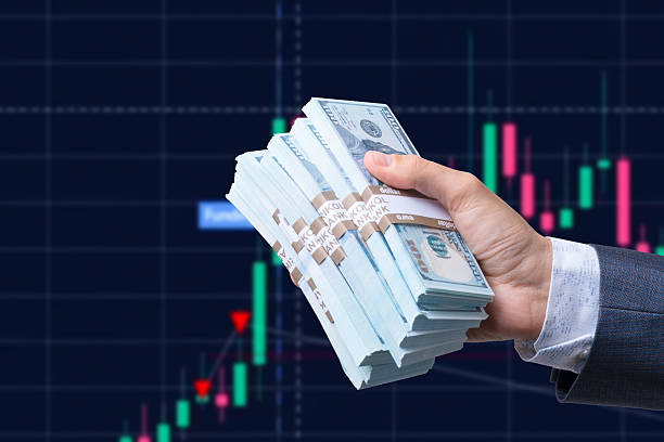 istock Man's hand holding Dollar (USD) banknotes on stock market background. 2220728276