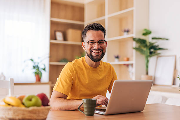 istock Young man smiling and working from home with laptop 2220730127