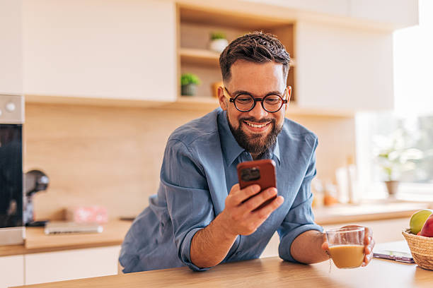 istock Young man enjoying morning coffee and browsing smartphone in kitchen 2220730385