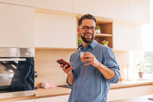 istock Smiling man enjoying morning coffee and checking smartphone in kitchen 2220730473