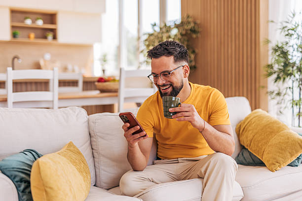 istock Young man relaxing on sofa, enjoying coffee and browsing smartphone at home 2220730832