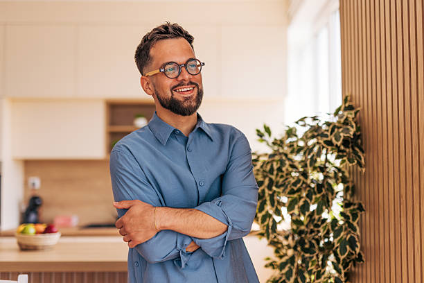 istock Young businessman smiling with folded arms in his modern apartment 2220731248
