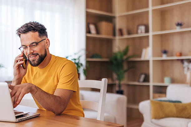 istock Freelancer talking on phone and working on laptop at home 2220731521