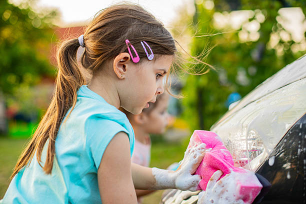 istock Kids Learning Responsibility by Washing Car with Pressure Hose 2220733178
