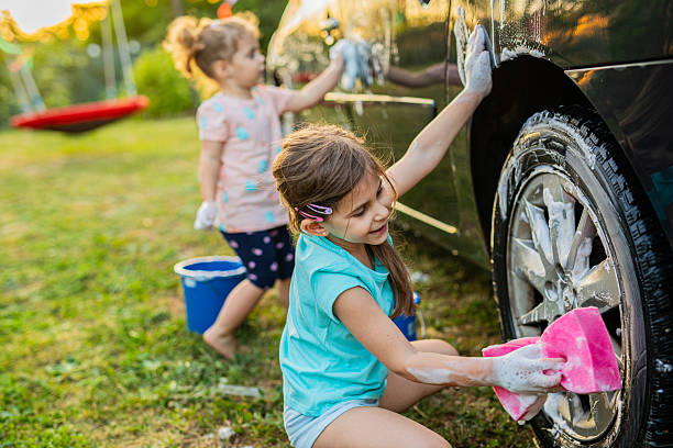 istock Kids Learning Responsibility by Washing Car with Pressure Hose 2220733440